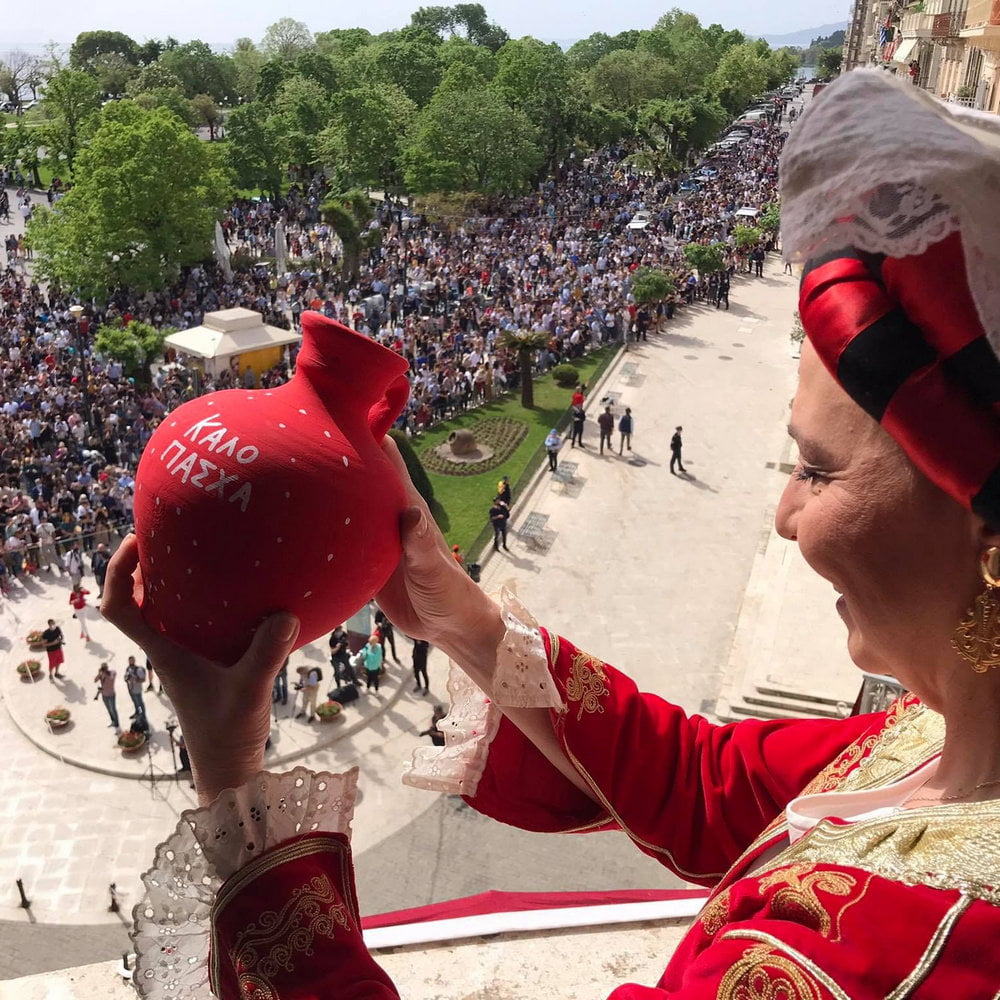 Woman in traditional Corfu costume throws a botis pot for Easter